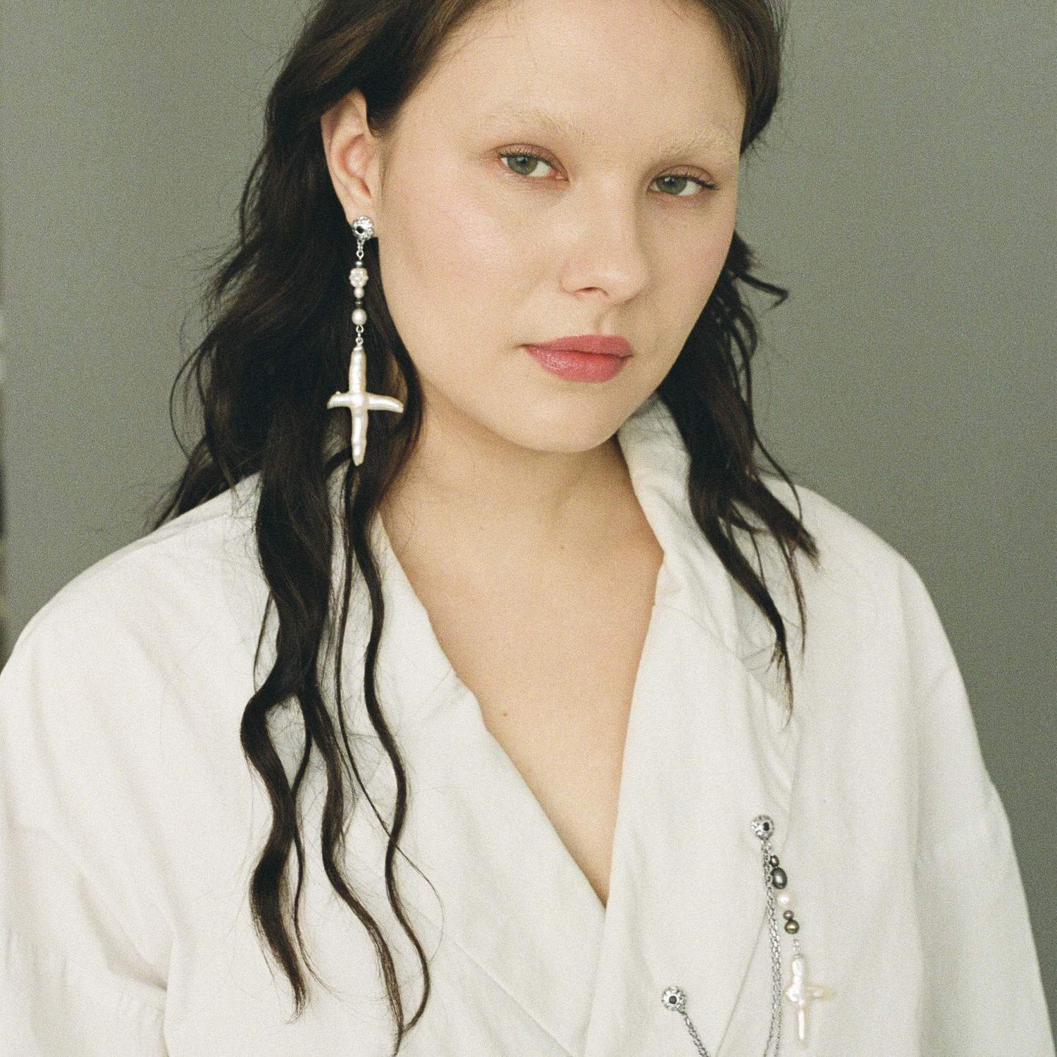 Asymmetrical freshwater cross pearl earring with sterling silver and black sapphire accents.