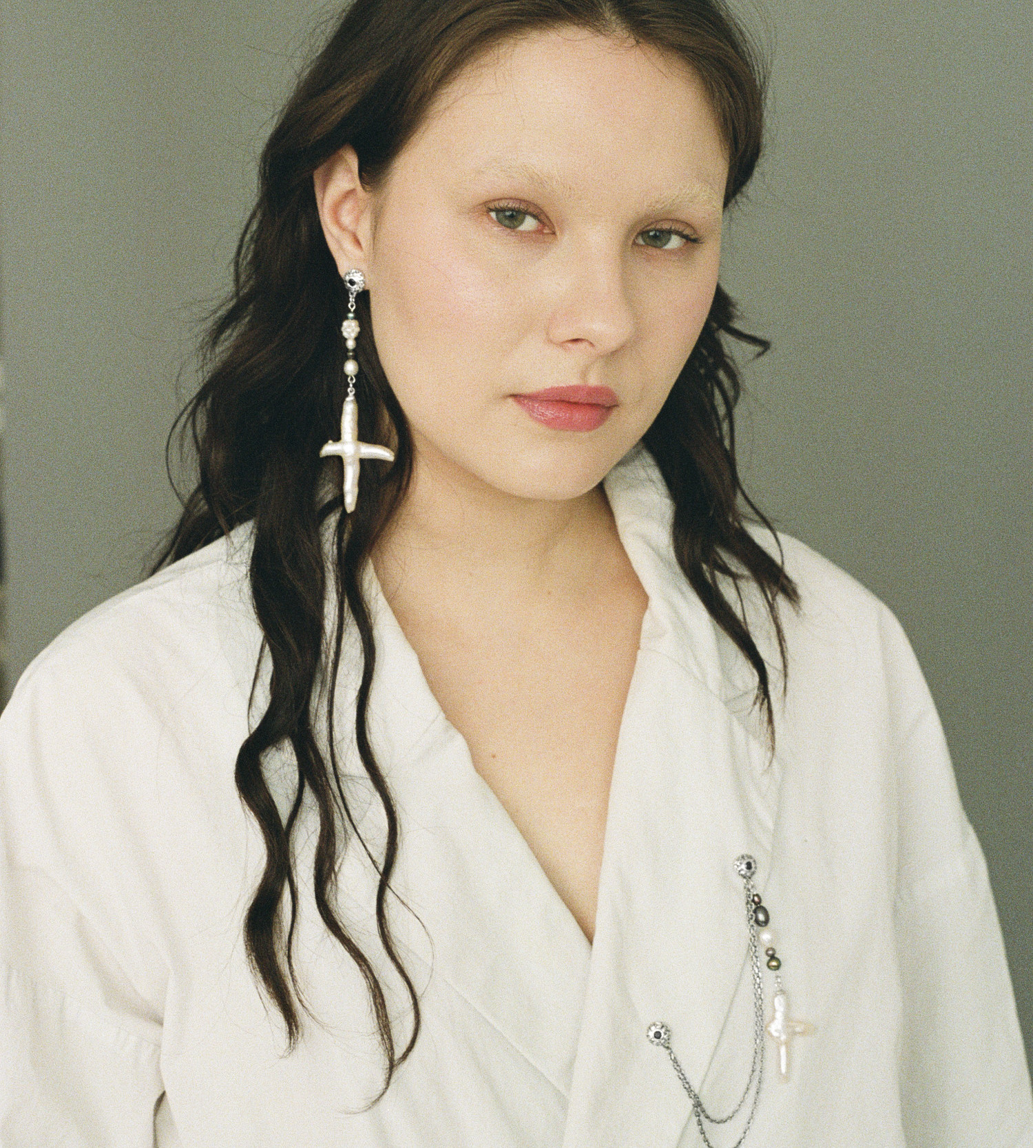 Asymmetrical freshwater cross pearl earring with sterling silver and black sapphire accents.