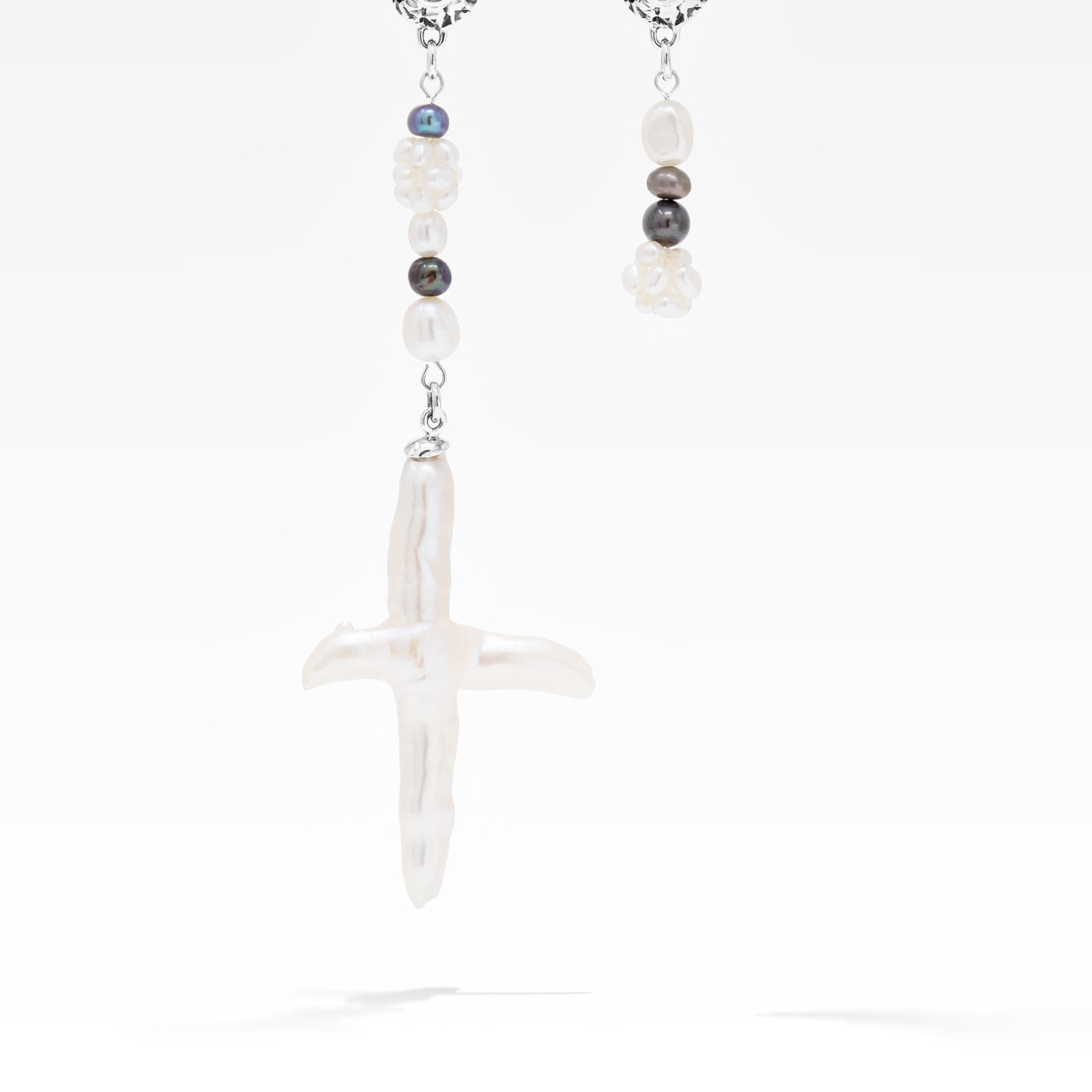 Asymmetrical freshwater cross pearl earring with sterling silver and black sapphire accents.