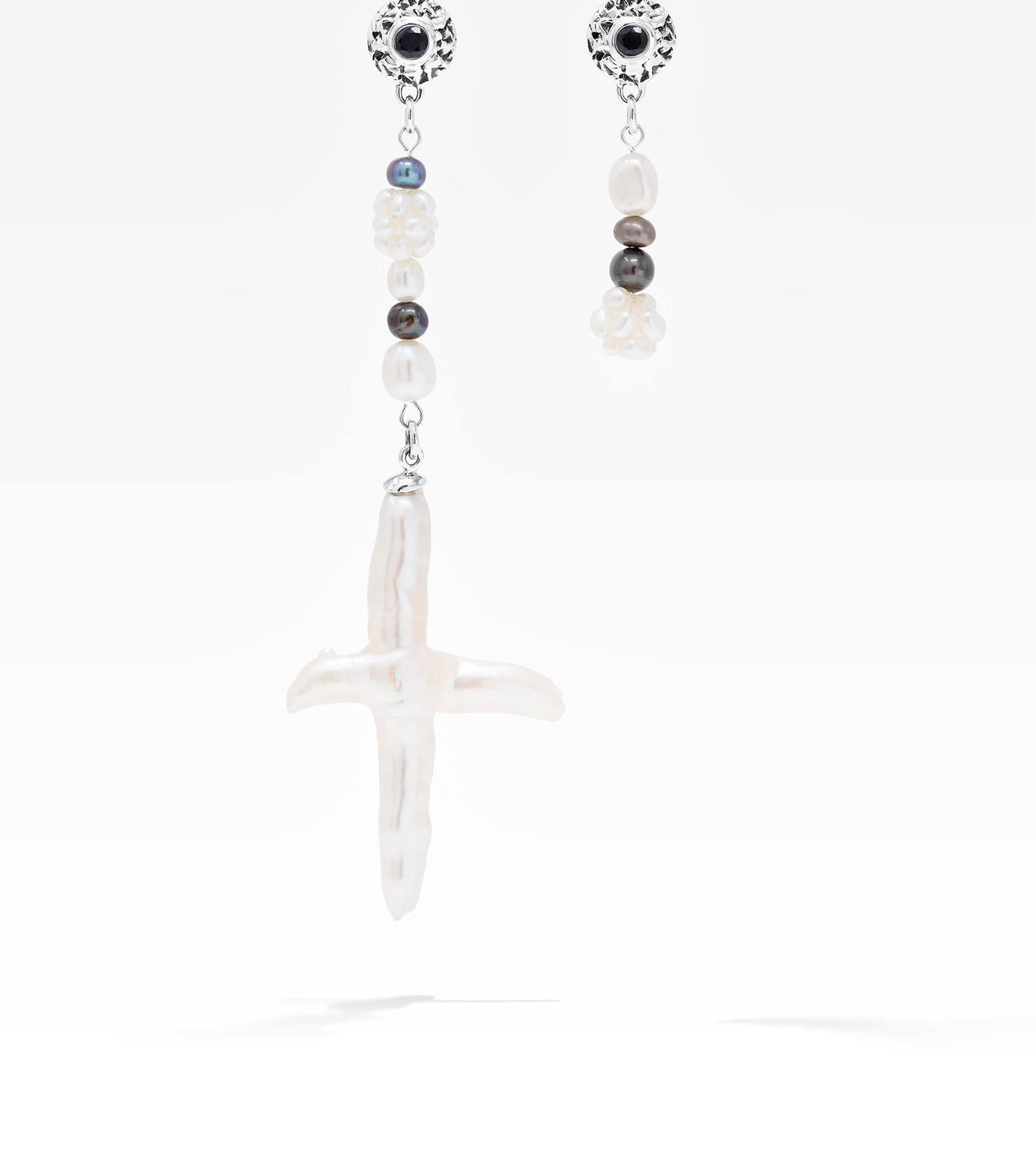 Asymmetrical freshwater cross pearl earring with sterling silver and black sapphire accents.