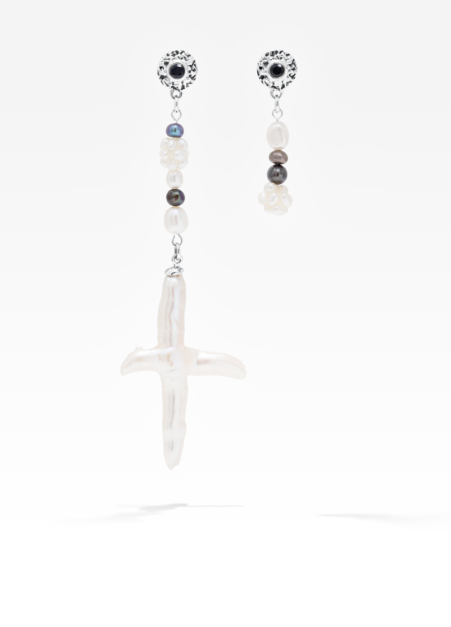 Asymmetrical freshwater cross pearl earring with sterling silver and black sapphire accents.