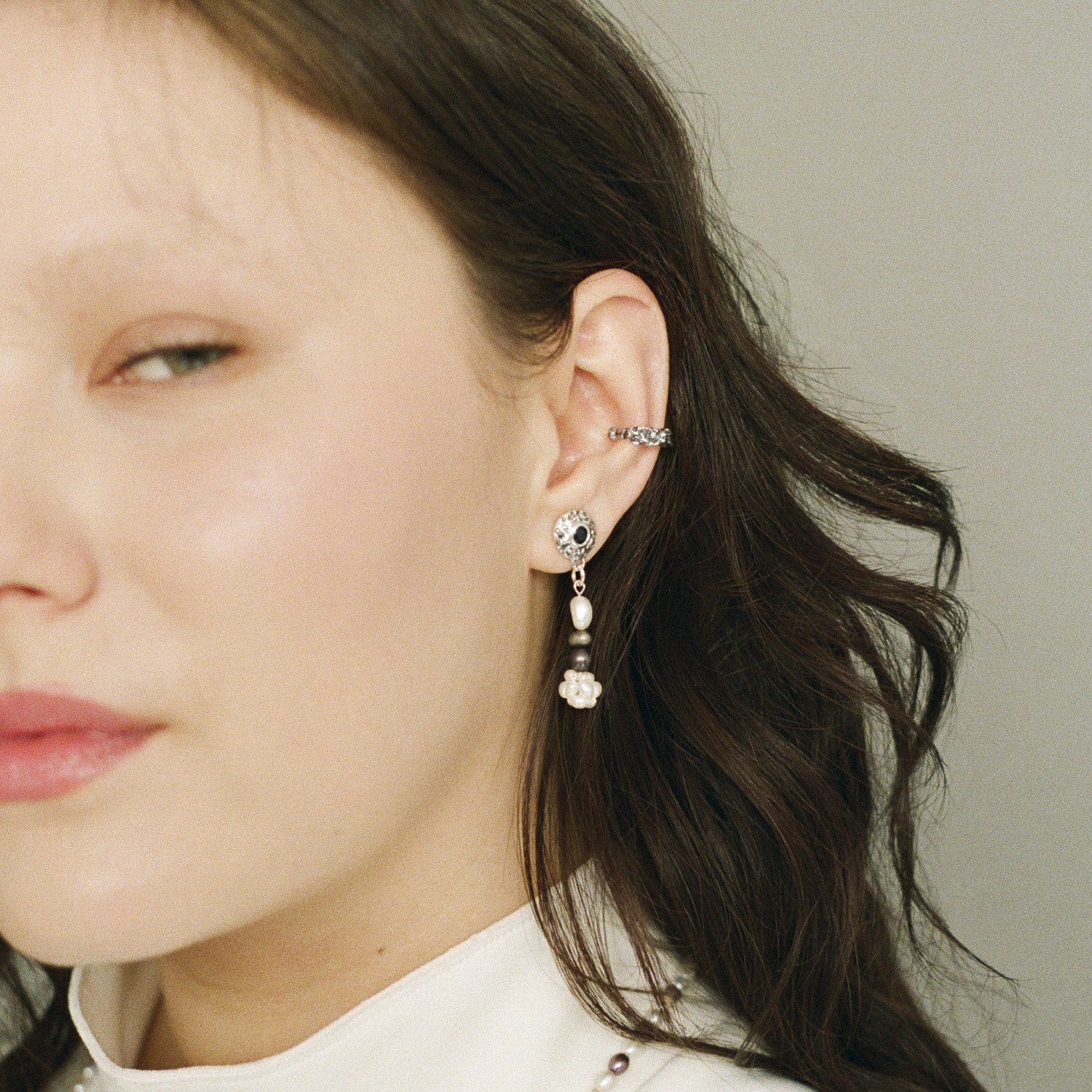 Asymmetrical freshwater cross pearl earring with sterling silver and black sapphire accents.