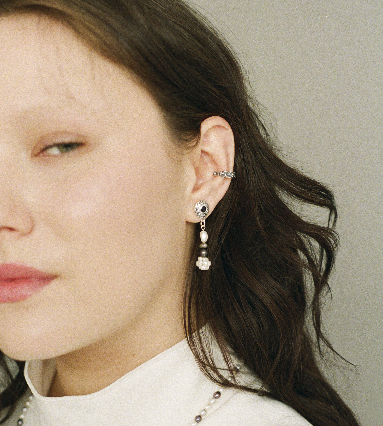 Asymmetrical freshwater cross pearl earring with sterling silver and black sapphire accents.